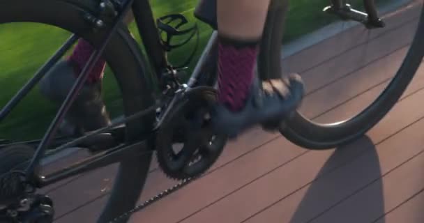 フィットネス女性は自転車のペダルを回しています。女性の足は速くペダルを漕いでいる。サイクリングギアを閉じてください。サイクリングチェーンとカセット。プロのサイクリストは、太陽の下でサイクリングをしています。トライアスロンのコンセプト — ストック動画