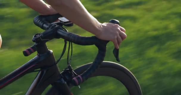 As mãos femininas estão segurando guidão de bicicleta de estrada. Mulher fitness está girando pedais de bicicleta. As mãos das mulheres seguram o guiador de ciclismo. Vista do guiador. Conceito desportivo. A mulher está de bicicleta. Treinamento de Ciclismo Feminino — Vídeo de Stock