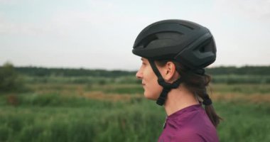 Genç çekici esmer kadın bisikletçi gün batımında bisiklete binmeden önce güneş gözlüğü takıyor. Siyah kasklı profesyonel triatlet bisiklet eğitiminden önce spor gözlüğü takıyor.