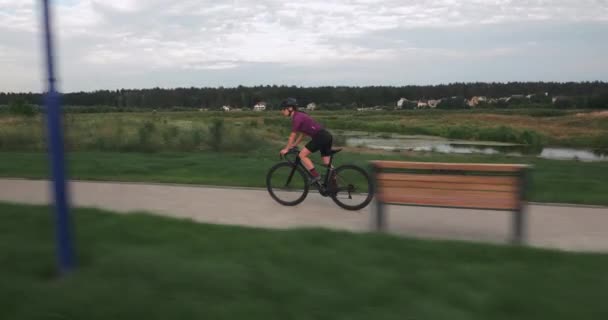 トライアスロン選手は速くロードバイクに乗っています。ハードワークだ。遊歩道沿いの自転車に乗って自転車に乗る若い女性。サイクリストの女の子はロードバイクでペダルを漕いでいる。女性サイクリストは自転車のトレーニングをしています. — ストック動画