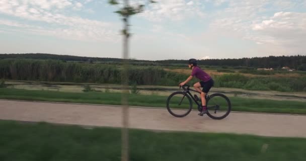 若いスポーツ女性はロードバイクに乗っています。フィットネス女性アスリートは夏に自転車でサイクリングしています。プロのサイクリストは自転車のトレーニングをしています。女の子は自転車に乗っている。トレーニングワークアウト. — ストック動画