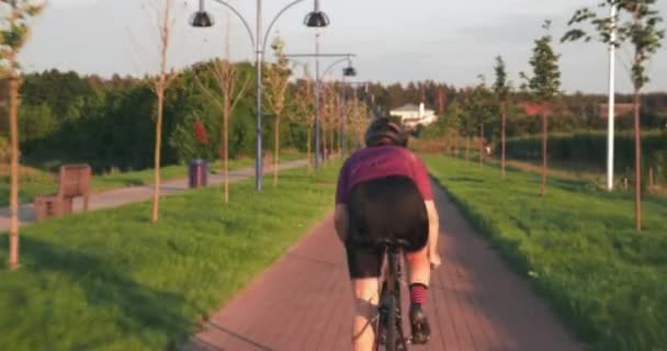 Profesjonalna rowerzystka ciężko pedałuje na rowerze. Sportowiec biegnie na rowerze. Triatlonista jedzie do przodu na rowerze o zachodzie słońca. Sportowiec trenuje sprint na rowerze. Trening rowerowy — Wideo stockowe