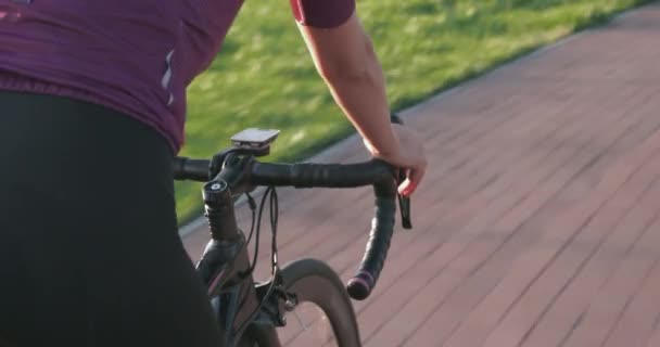 Vrouw is aan het fietsen. Herstel fietstocht in park in de zon. Vrouwelijke ritten op de racefiets. Close-up zicht op het stuur van de aero bike. Fietshanden zijn op het stuur van de fiets. Meisje beweegt voorwaarts op cyclus — Stockvideo