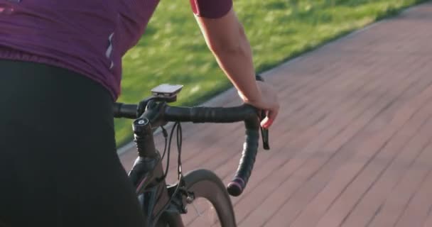 La mujer está en bicicleta. Recuperación paseo en bicicleta en el parque bajo el sol. Paseos femeninos en bicicleta de carretera. Vista de cerca del manillar de la bicicleta aerodinámica. Las manos del ciclista están en el manillar de la bicicleta. Chica avanza en el ciclo — Vídeo de stock