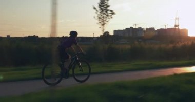 Kadın gün batımında bisiklet yolunda bisiklet sürüyor. Genç çekici kız gün ışığında bisiklet sürüyor. Profesyonel triatlet gün doğumunda motorsiklet eğitimi alıyor. Bisiklet ve triatlon konsepti