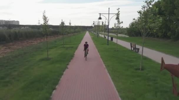 Radfahrerin rast mit Rennrad auf Promenade Radfahrerin ist bei Sonnenuntergang auf Fahrrad unterwegs. Glückliches Mädchen fährt Fahrrad. Gesunder Lebensstil. Rad- und Triathlonkonzept. Radtraining — Stockvideo