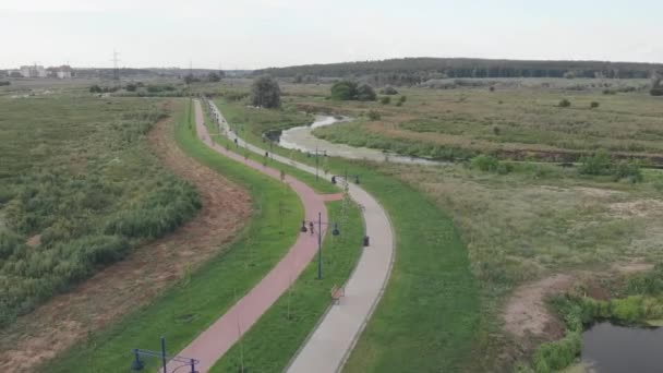 Giovane donna atletica in forma in bicicletta sulla pista ciclabile. Atleta sportiva femminile in casco e abbigliamento ciclistico cavalca su bici da strada aero, fa cardio duro allenamento, si prepara a correre in bicicletta nel parco — Video Stock