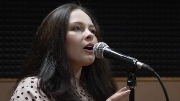 Woman is singing into microphone in professional recording studio. Singing girl with microphone in rehearsal studio. Glamour professional female singer is practicing in vocal studio. Music concept — Stock Video