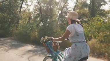 Antika eski bisikletle eğlenceli bir gezinti. Genç ve güzel bir kadın gün batımında bisiklet sürüyor. Retro tarzı. Büyüleyici romantik kız yaz parkında bisiklet sürüyor. Sunset Ormanı 'nda antika bisikletli bir kız.