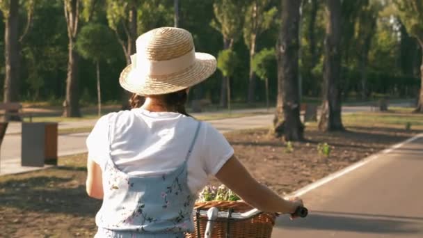 Stylový okouzlující žena cyklista je šlapání na cyklistické stezce v městském parku při západu slunce. Bezstarostné usmívající se dívka je cyklistika na staré staré kolo při východu slunce. Žena jezdec jezdí retro kolo v parku na slunci — Stock video