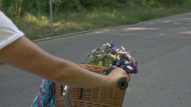 快乐无忧无虑的女人正在放松和骑复古自行车。穿着夏装戴帽子的骑自行车的女孩骑着装有花篮的旧自行车。假期愉快。快乐的女人骑自行车 — 图库视频影像