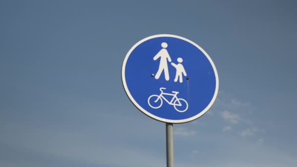 Yaya geçidi ve mavi gökyüzüne karşı bisiklet yolu tabelası, aşağıdan yakın görüş. Bisiklet ve yaya yolu işaretleri. Mavi arka plana karşı yol işareti yayalar ve bisikletçiler — Stok video