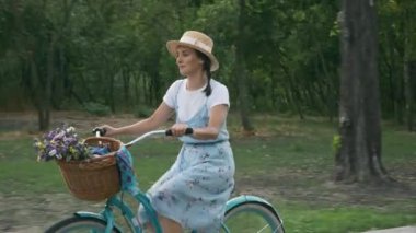 Fitness büyüleyici bisikletçi gün ışığında bisikletle pedal çeviriyor. Genç bir kadının portresi günbatımında bisiklet yolunda eski model bir bisiklette pedal çeviriyor. Mutlu motive olmuş kadın bisiklete biniyor.