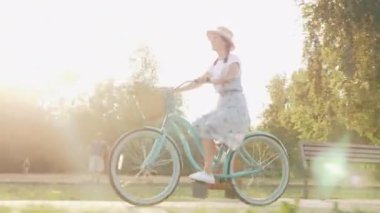 Mutlu neşeli kadın klasik bisiklete biniyor ve yazın dışarıda eğleniyor. Parkta eski bir bisiklette sağlıklı ve aktif yaşam tarzı olan çekici bir kız. Güneşte retro motorlu bir bayan