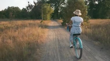 Kadın bisikletçi park yeşil alanında eski bir bisiklete biniyor. Mutlu gülümseyen kız, sepetinde bir buket çiçekle Country Road 'da klasik bir bisikletle bisiklet sürüyor. Ekoloji konsepti. Temiz havada mutlu bir hafta sonu.