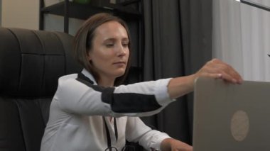Kendine güvenen akıllı iş kadını dizüstü bilgisayarı açıyor ve gözlüklerini takıyor, ofis masasında çalışmaya başlıyor. Genç ve çekici bir bayan ofiste dizüstü bilgisayar kullanıyor.