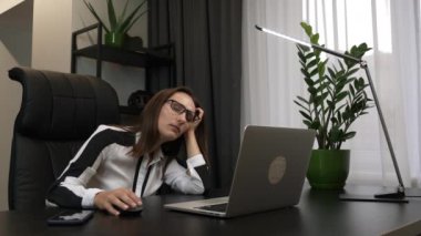 Yorgun kadın neredeyse sandalyeden düşecek. Sıkıcı iş kadını ofiste çalışmaya çalışıyor. Uyuyan kadın iş yerinde gözlerini ovuşturuyor. Yorgun kadın çalışanlar bilgisayar başında çok çalışıyor.