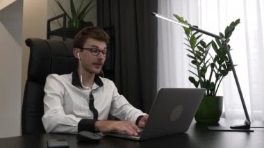 Kulaklıklı genç adam ofis masasından web kamerasıyla çevrimiçi grup görüşmesi yapıyor. Erkek işletme koçu konferans sırasında internet üzerinden konuşuyor ve webinarları kaydediyor.