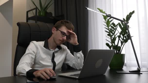 Zmęczony przepracowany człowiek pociera oczy w biurze. Wyczerpany biznesmen jest przepracowany na komputerze w swoim nowoczesnym biurze. mężczyzna pracownik zdejmuje okulary i masuje oczy po ciężkim dniu pracy — Wideo stockowe