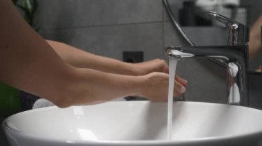 Kadın ellerini yıkıyor ve köpürüyor, parmaklarını lavaboda sabunla ovuyor. Coronavirus salgını önleme. Dişi, ellerini lavaboda köpükle yıkar cildini yıkamak için ve su ellerinden akar.