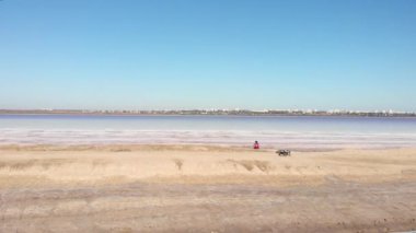 Kuyalnik Gölü 'nün inanılmaz tuzlu ve dişi bisiklet yolcusuyla hava aracı görüntüsü deniz kıyısının kenarında duruyor. Pembe suyu olan tuzlu deniz kıyısı. Güzel doğa.