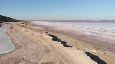 Bisiklet sürücüsü tuzlu gölün deniz kıyısında oturuyor. Pembe su Kuyalnik, hava aracı manzaralı. Ukrayna 'nın inanılmaz güzel doğası