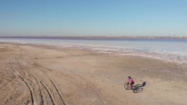 Ukrayna 'nın tuz gölü Kuyalnik kıyısında bisiklet süren bir kadın var. Bisikletli gezgin, kurumuş Kuyalnik Estuary kıyısı boyunca bisiklet sürüyor. Güzel doğa.