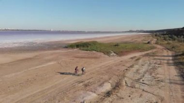 Gezginler Kuyalnik 'te bisiklet sürüyor, hava aracı manzaralı. Bisiklet sürücüleri Ukrayna 'nın Odessa kentindeki Kuyalnik Liman üzerinde kurumuş tuz kıyısı boyunca seyahat ediyorlar. Güzel Ukrayna özgün doğası