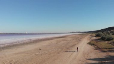 Turist, Kuyalnik haliçlerinin Karadeniz 'inde gelgit sırasında bisiklete biniyor. Odessa, Ukrayna 'daki çamur banyosu kliniği. Kuyalnik 'in tuzlu kıyılarının kadın bisikletli hava aracı görüntüsü