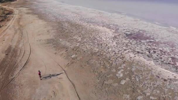 Reiziger rijdt op de fiets op zoute oever van het droogmeer Kuyalnik, Oekraïne. Ongelooflijk mooie natuur. Luchtfoto drone uitzicht op de kust van Kuyalnik estuarium, Odessa — Stockvideo