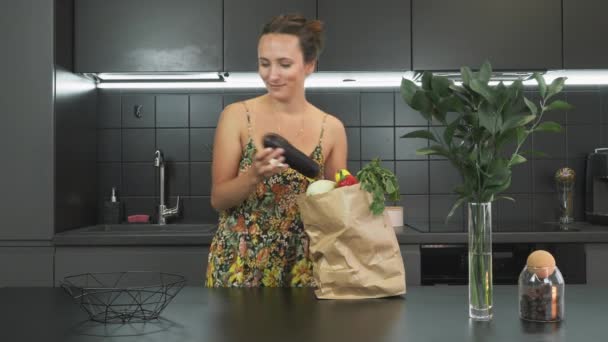 Portrait de jeune femme est le déballage des produits et des légumes de sac en papier d'épicerie réutilisable artisanat dans la cuisine sur une table en bois. Zéro déchet maison et sac écologique. Eco Shopping — Video