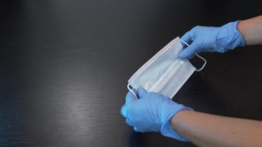 Mavi tek kullanımlık eldivenli eller koruyucu maske tutuyor, nasıl maske kullanılacağını gösteriyor. Covid-19 Koruma, tıbbi maske bilim adamı ya da doktorun elinde.