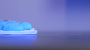 Mavi tek kullanımlık eldiven, mobilya yüzeyini ıslak mendil ve dezenfektanla dezenfekte ediyor. Temizlikçi kadın virüs enfeksiyonu ve koronavirüs covid-19 salgınını önlemek için odayı dezenfekte ediyor.