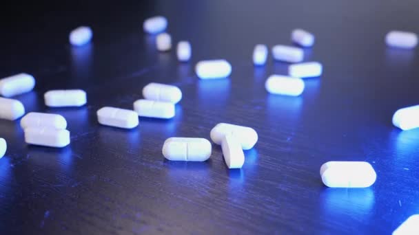 Fehér tabletták hullanak az asztalra. A drogok fekete háttérbe szorulnak. Orvosi és gyógyszerészeti üzleti koncepció. Gyógyszeripar. Coronavirus vakcina. Tabletták és gyógyszerek — Stock videók