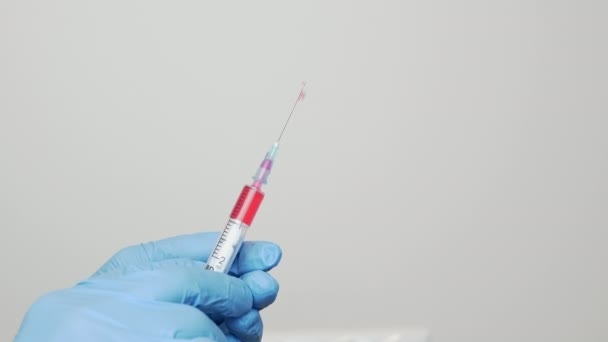 科学家们手拿着蓝色一次性医用手套，用针头注射器进行近距离检查，采集疫苗样本。药物研究的概念。Covid-19 Coronavirus预防保护 — 图库视频影像