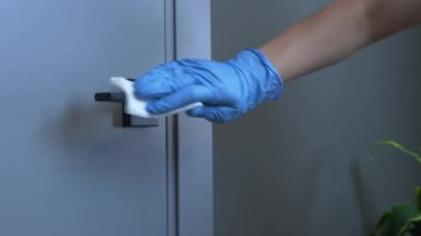 Plastik eldivenli kadın eller kapı kolunu dezenfekte ediyor. Coronavirus salgını, covid-19 önleme koruması. Tek kullanımlık eldivenleri olan kadın salgın sırasında kapıyı sterilize ediyor.