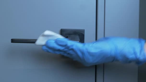 A mulher está higienizando a maçaneta da porta usando toalhete úmido e spray desinfetante de álcool. As mãos femininas estão desinfetando e limpando a sala para evitar a pandemia do vírus. Coronavírus, epidemia de covid-19, infeções por gripe — Vídeo de Stock