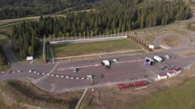 Yeşil çam ağaçları ormanı olan dağlardaki biatlon eğitim üssü. Yazın biatlon için spor pisti. Ormanda spor kampı, hava aracı manzarası.