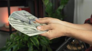 Kadın elleri 100 dolarlık banknotları tutuyor. Kadın nakit para sayıyor. Dünya ekonomik krizi. Büyük para yığını. Kadın ellerine yakın bir yerde nakit para var.