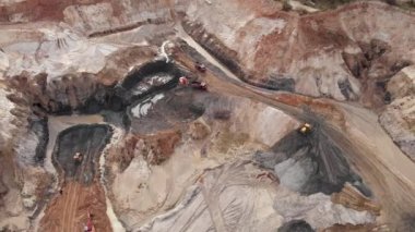 Demir cevheri ocağı açık maden ocağı. Kazı makinelerinin ve makinelerin hava görüntüsü taş ocağındaki çöp kamyonuna maden cevheri yüklüyor. Büyük endüstriyel taş ocağı