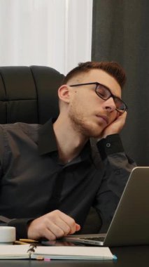 Yorgun adam iş yerinde neredeyse uyuyakalıyordu ve telefonla uyandı. Erkek çalışan az kalsın ofis masasından düşüyordu, işte çok çalışıyordu ve yorgundu. Dikey video