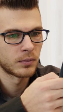 Akıllı telefonu elinde tutan ve dizüstü bilgisayarın önünde mesajlar yazan bir adam. Ofiste çalışan bir iş adamı. Dikey