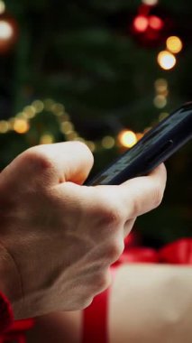 Akıllı telefonu elinde tutan ve internetten Noel hediyesi alan bir kadın banka kartıyla ödeme yapıyor. Noel arifesinden önce internetten alışveriş yapan bir kadın. Dikey video