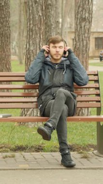 Genç yakışıklı adam kulaklıklarını takar ve sonbahar şehir parkında bankta otururken müzik dinlemeye başlar. Dikey video