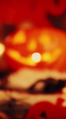 Cadılar Bayramı balkabağı gibi, içinde mum ateşi olan ürkütücü yüzler. Yarasalar ve örümceklerle cadılar bayramı süsleri. Cadılar Bayramı selamları. Dikey video