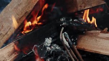 Ateşte yakacak odun. Parlak ateş alevleriyle ahşap odunlar yakıyor. Ateş şenlik ateşinde yanıyor. Barbekü ve ızgara konsepti. Dikey video