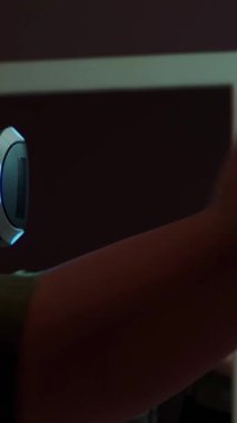 İnteraktif oyun oynayan genç bir kadın oyun kumandası kullanarak VR gözlüğü takıyor. Gözlüklü kız evde sanal gerçeklik eğitimi alıyor. Kadın oturma odasında video oyunu oynuyor. Dikey video