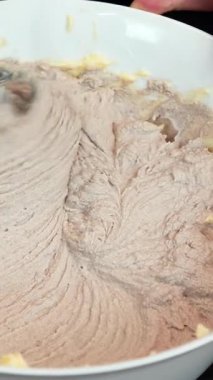 Pastacı tereyağı çırpıyor ve elektrikli el karıştırıcısı kullanarak sıcak çikolata yapıyor, pasta yapıyor. Kakao kremalı pasta hazırlayan kadın. Tatlı tatlı pişirme süreci. Dikey video