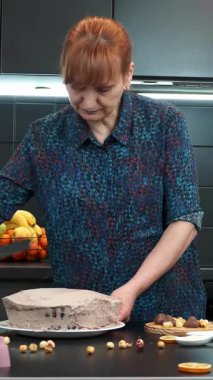 Kremalı çikolatalı pasta yapan kadın fırıncının portresi. Pasta şefi tereyağlı ev yapımı kremalı kek pişiriyor. Çikolatalı pasta dekore eden bir şekerci. Dikey video