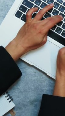 Kadın dizüstü bilgisayarda yazmayı bırakıp dizüstü bilgisayarı kapatıyor, üst görüntüyü kapatıyor. Ofiste çalışan bir kadın. Dikey video